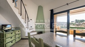 A spacious room with a large window, a dining table, and a television. - 18BAIADELFARO - 18 BAIA DEL FARO (Palau)