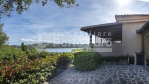 A stone pathway leading to a building with a covered patio area. - 20E Appartamento - 20E Porto Mannu (Palau)