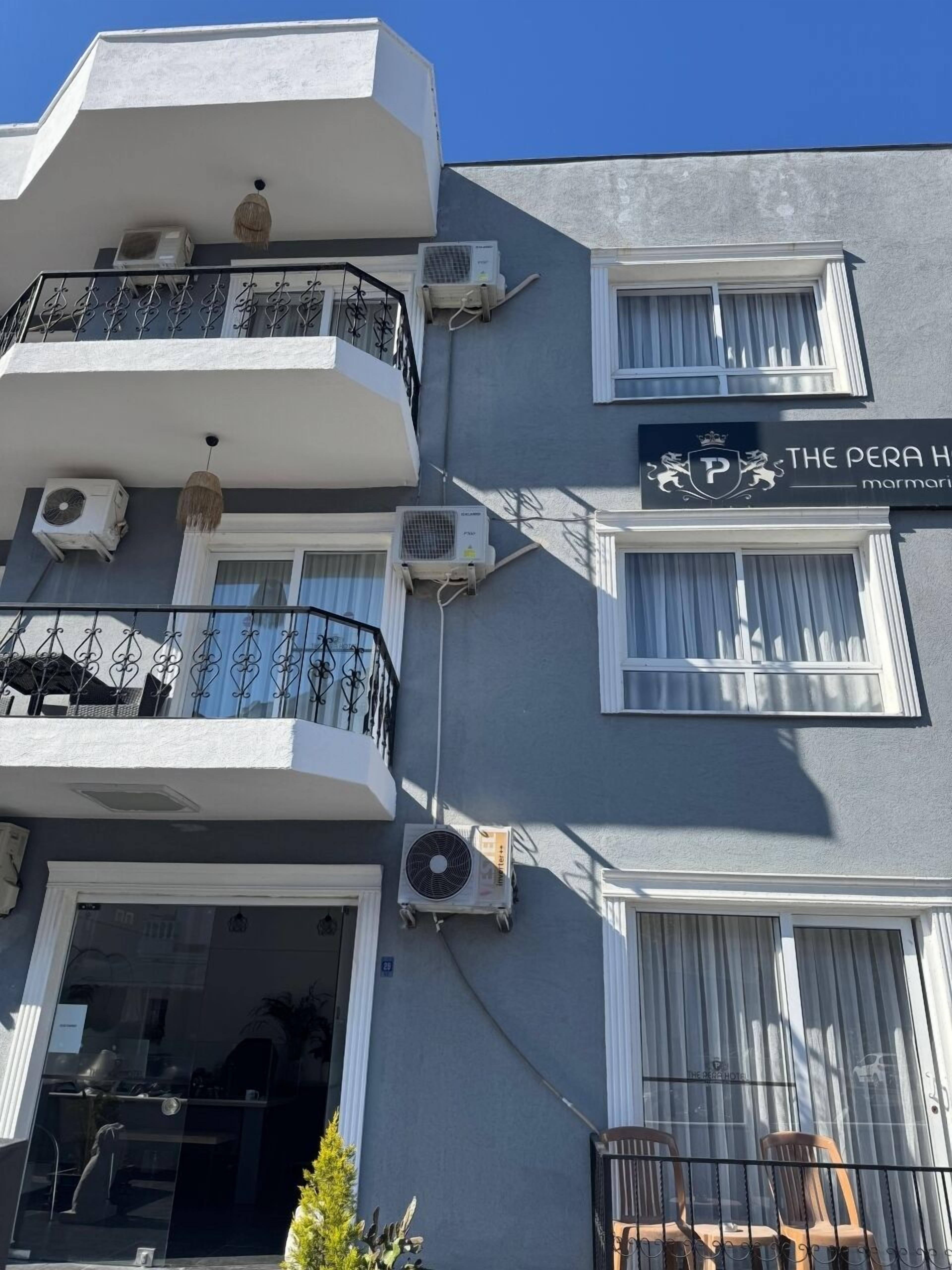 A multi-story building with balconies, air conditioning units, and a sign for "The Pera Hotel".