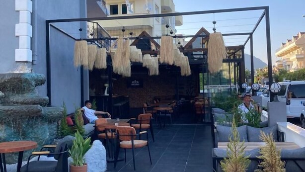 An outdoor seating area with tables and chairs, a stone wall, and hanging decorations. - The Pera Hotel Marmaris (Marmaris)