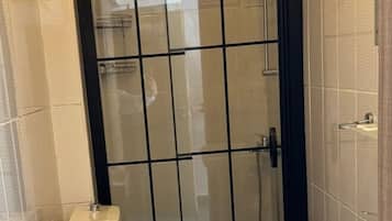 A small bathroom with a toilet, a sink, and a shower area.