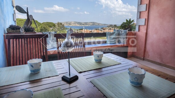 Ein Balkon mit Meerblick, einem Tisch, einem Stuhl und einer dekorativen Vogelstatue.
