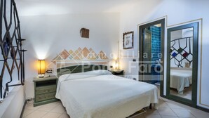 Ein Schlafzimmer mit einem Bett, zwei Nachttischen mit Lampen, einem Spiegel und einer Tür zum Badezimmer.