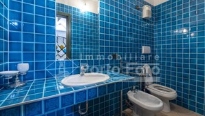 Un baño con azulejos azules, un lavabo, un inodoro y un bidé.