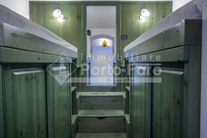 A narrow corridor with wooden walls and a central staircase leading to a door with a yellow diamond-shaped sign.