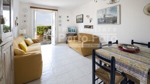 Un salón amplio con un sofá, una mesa de comedor con sillas y vistas al exterior.