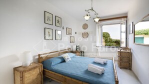 Un dormitorio con una cama de madera, una mesita de noche, una lámpara, un ventanal con vistas y decoración en la pared.