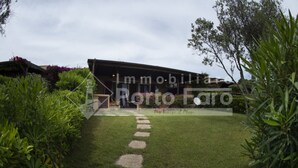 A residential property with a paved driveway leading to a covered porch, surrounded by lush greenery. - 7A Appartamento - 7A PORTO MANNU (Palau)