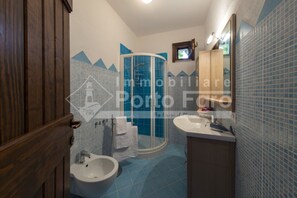 A bathroom with a shower, bidet, and sink.