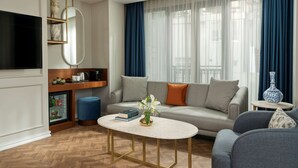 A modern living room with a sofa, a coffee table, a television, and a small side table with a vase.