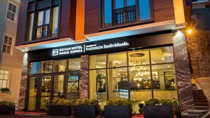 A modern hotel with a prominent entrance, large windows, and a stone facade.