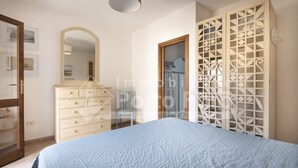 A bedroom with a bed, dresser, mirror, and decorative screen. - L304 Appartamento - L304 PORTO MANNU (Palau)