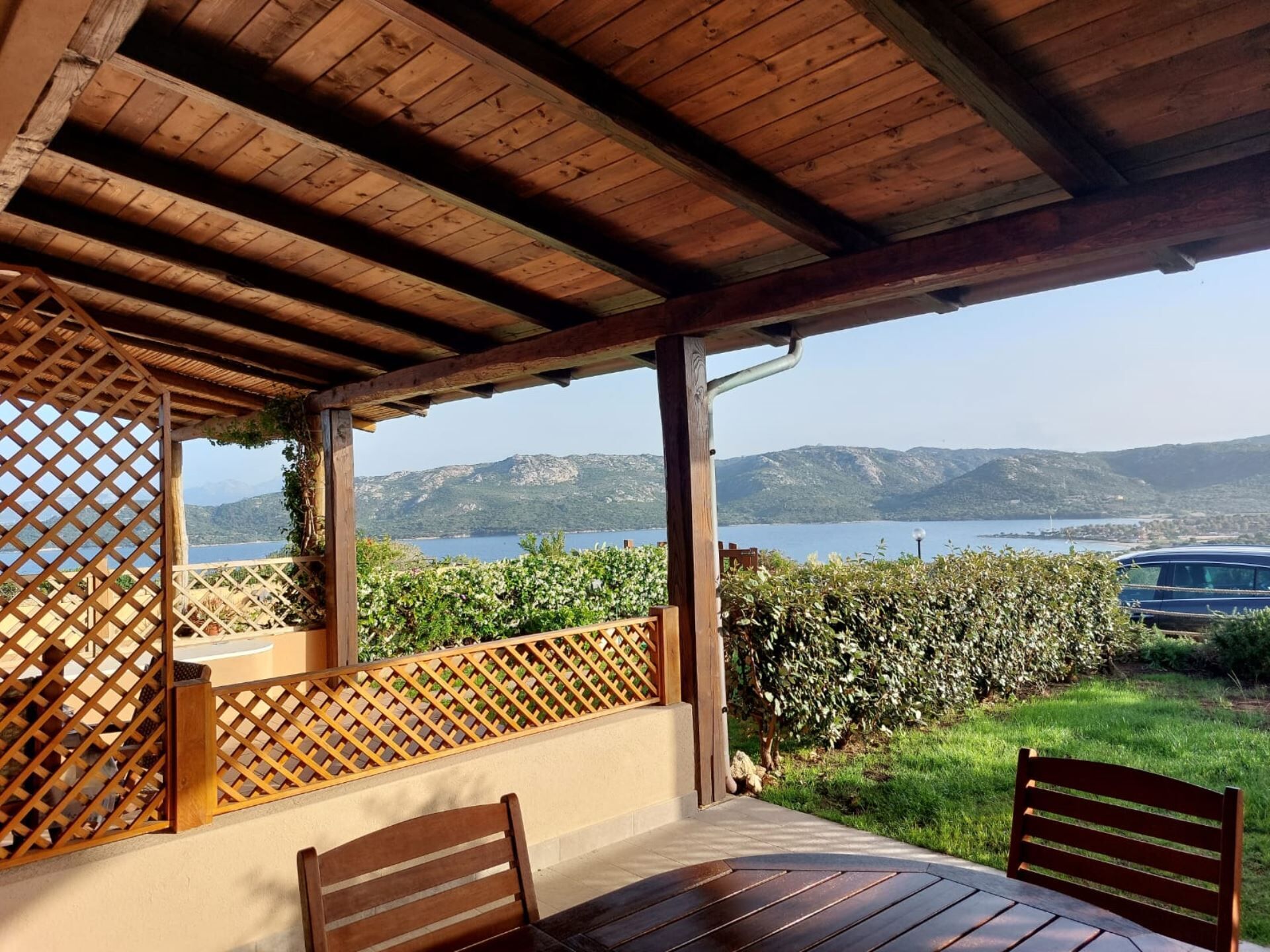 A covered outdoor seating area with a view of a lake and mountains.