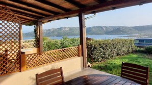 A covered outdoor seating area with a view of a lake and mountains. - L304 Appartamento - L304 PORTO MANNU (Palau)