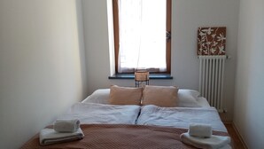 A bedroom with a large bed, a window with curtains, a radiator, and a wall decoration. - ex scuola ristrutturata di recente (PAULARO)