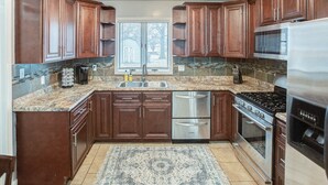 Una cocina con armarios de madera oscura, un refrigerador de acero inoxidable, una estufa a gas y un lavavajillas.