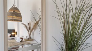 A dining area with a white table, wicker pendant light, and a potted plant. - Little Beach House - Great couples getaway! (Zandvoort)