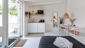 A modern, open-plan living space with a kitchen, dining area, and a large bed. - Little Beach House - Great couples getaway! (Zandvoort)
