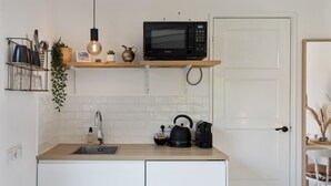 A modern kitchen with a microwave, kettle, and sink. - Little Beach House - Great couples getaway! (Zandvoort)