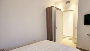 A bedroom with a bed, a wardrobe, and a television on the wall. - Appartamento Ariel   La Perla del Mare di Polignano (Polignano a Mare)