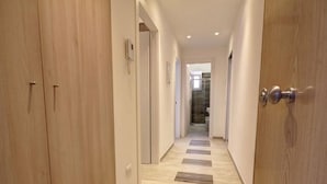 A hallway with wooden doors, a phone on the wall, and a tiled floor. - Appartamento Ariel   La Perla del Mare di Polignano (Polignano a Mare)