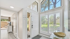 Et moderne interiør med en glasdør, der fører ud til en balkon, en hvid dør og et glastbord med en skål.