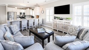 Une cuisine moderne avec des meubles blancs, des appareils en acier inoxydable et un coin bar agrémenté de chaises en osier.
