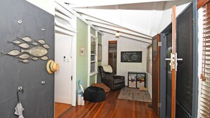Un couloir avec un plancher en bois, une porte noire et un mur décoré de poissons et d’un chapeau.