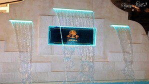 Un élément décoratif aquatique agrémenté de panneaux illuminés, installé dans un espace piscine.
