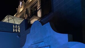 Vue nocturne d’un bâtiment agrémenté d’un élément aquatique dont l’eau s’écoule en cascade le long d’un mur à texture.
