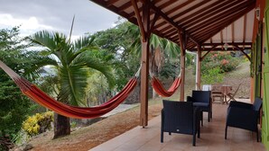 Un espace extérieur aménagé, abrité et doté de mobilier en osier, d  ’un hamac et offrant une vue sur la végétation tropicale.