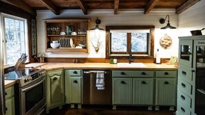 A kitchen with wooden cabinets, a sink, and a stove. - JuneBug Log Cabin, Nashville Music History, Dreamy Loft Suite, Stone Frpl. (Hendersonville)