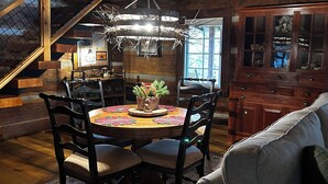 A rustic dining area with a wooden table, chairs, and a chandelier. - JuneBug Log Cabin, Nashville Music History, Dreamy Loft Suite, Stone Frpl. (Hendersonville)
