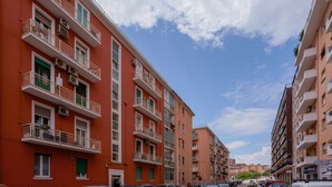 Un edificio residencial de varios pisos con balcones, unidades de aire acondicionado y cielo despejado.