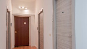 Un pasillo con piso de madera y dos puertas, una con un cartel encima.