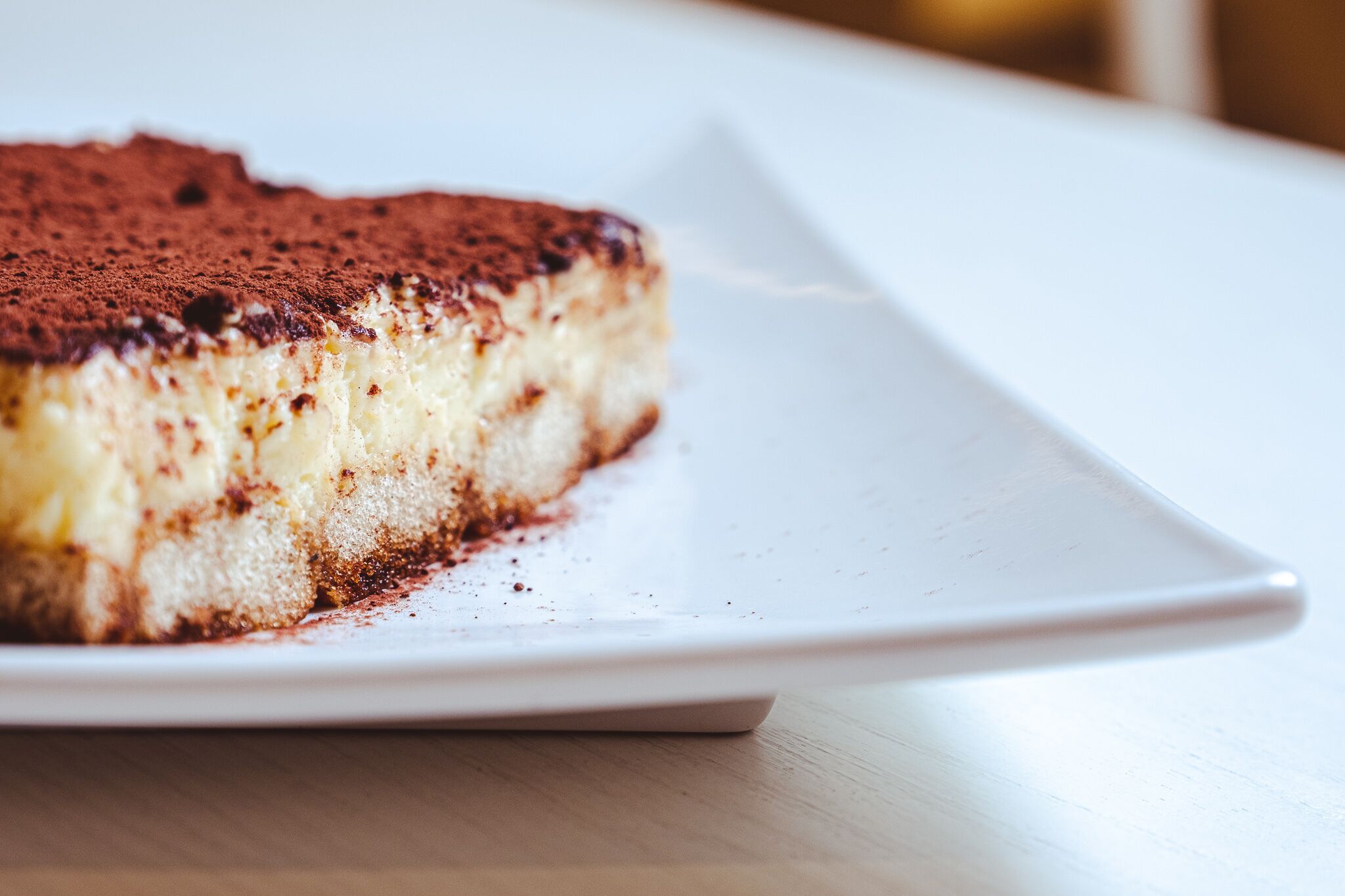 En bit tiramisu på en vit tallrik.