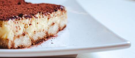 En bit tiramisu på en vit tallrik.