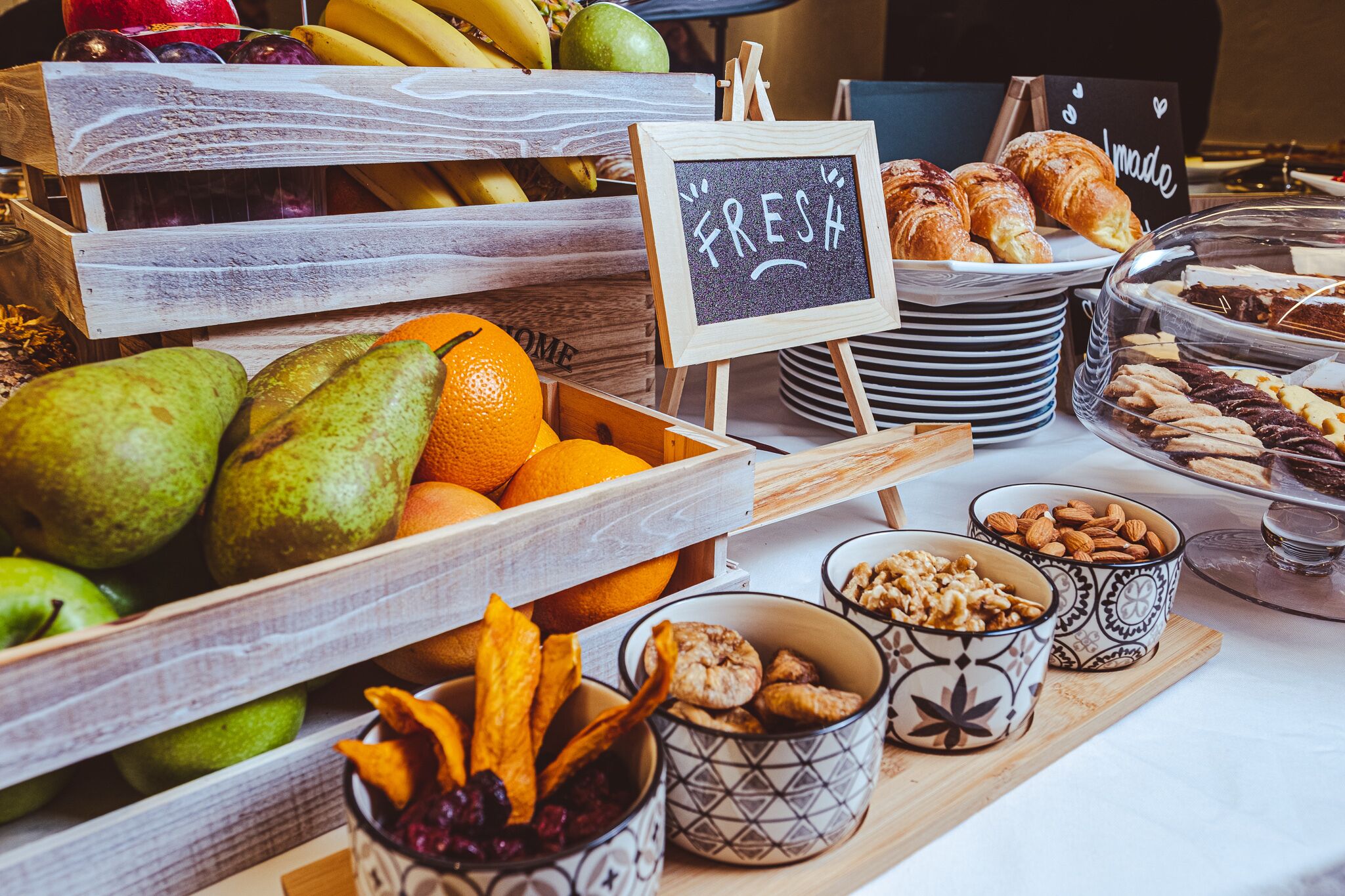 Een ontbijtbuffet met vers fruit, gebak en noten.