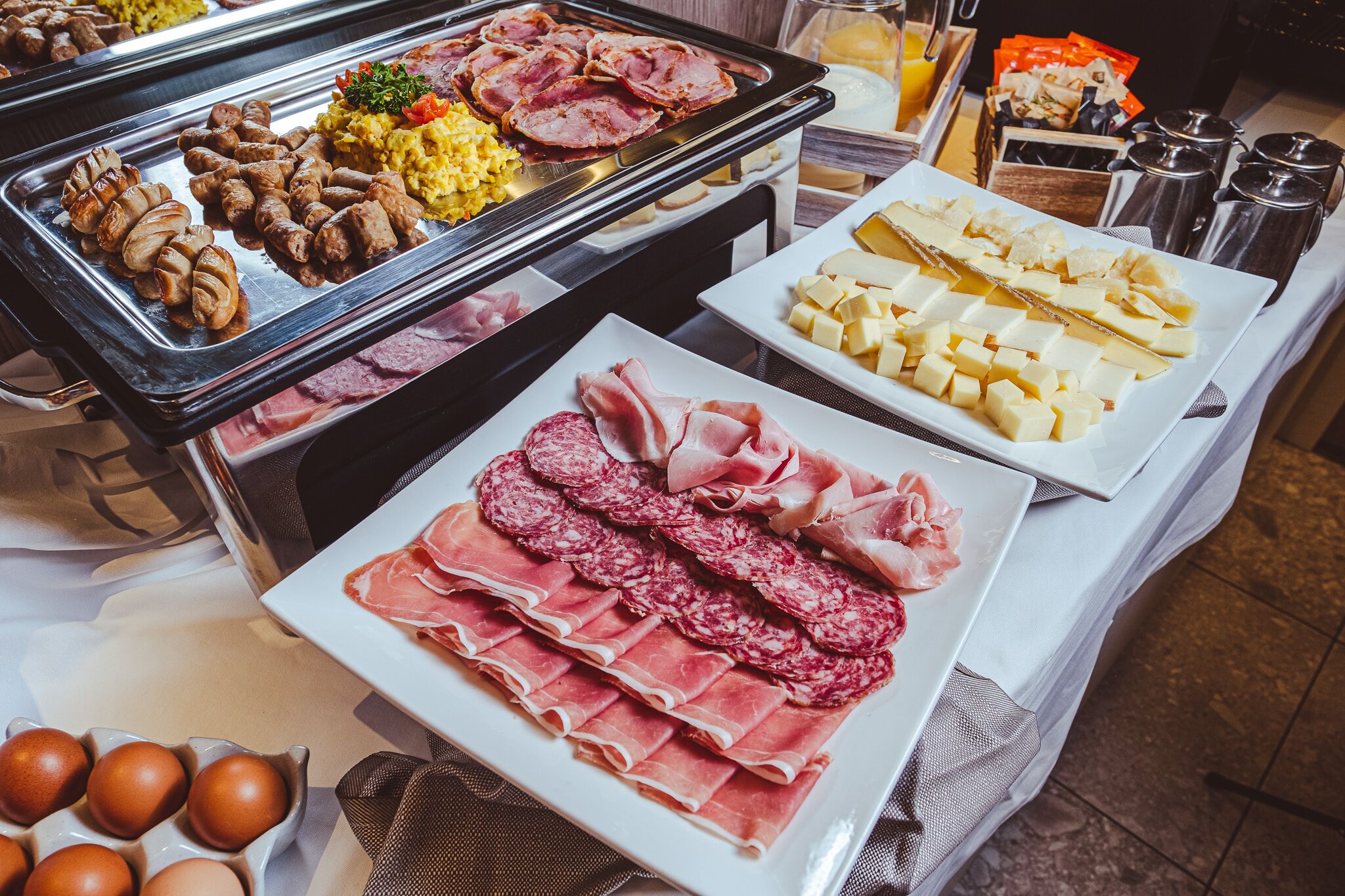 Un bufé con diferentes carnes, quesos y huevos.