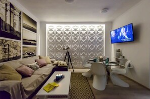 Una sala de estar moderna con un sofá, una mesa de centro, un televisor y una pared con estampado.