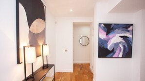 A hallway with a bench, a round mirror, and a painting on the wall. - Stylish West End Flat in Glasgow (Glasgow City)
