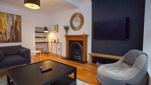 A living room with a sofa, a coffee table, a fireplace, and a television. - Stylish West End Flat in Glasgow (Glasgow City)