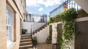 A courtyard with a staircase, potted plants, and a metal fence. - Stylish West End Flat in Glasgow (Glasgow City)