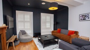 A modern living room with a sofa, coffee table, and a grey bean bag. - Stylish West End Flat in Glasgow (Glasgow City)