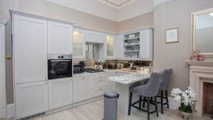 A modern kitchen with white cabinetry, a marble island, and two bar stools. - Charming 3-Bedroom Retreat in Glasgow West End (Glasgow City)