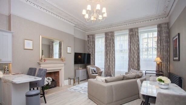 A spacious living room with a sofa, dining table, and TV. - Charming 3-Bedroom Retreat in Glasgow West End (Glasgow City)