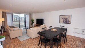 A modern living room with a sofa, a dining table, and a TV.