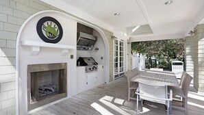 Un patio couvert avec un barbecue, un coin salon et une cheminée.