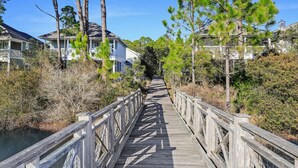 Une promenade en bois qui mène à un quartier résidentiel, avec des maisons et un plan d’eau.