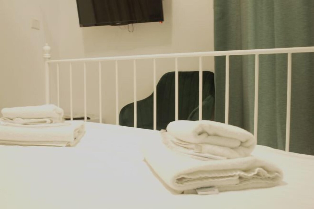 A hotel room with two beds, each with neatly folded white towels.